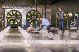 Three men work inside a large wind tunnel